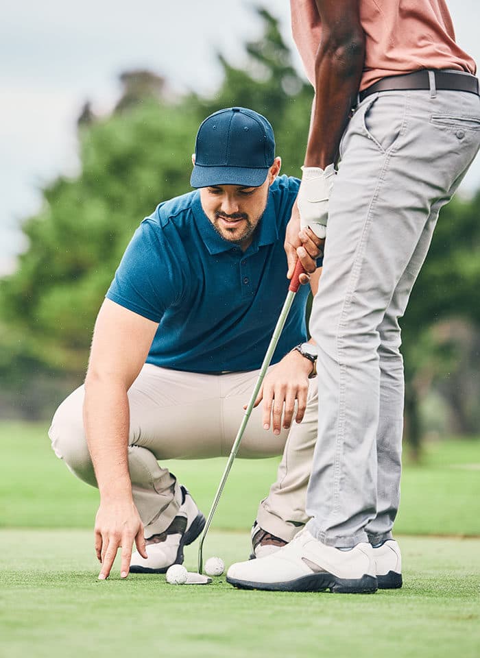 An instructor working with a golfer on the range.